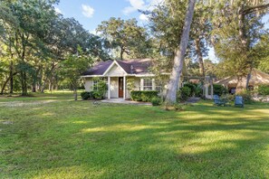 A single-story house with a front porch, surrounded by a well-maintained lawn and trees.