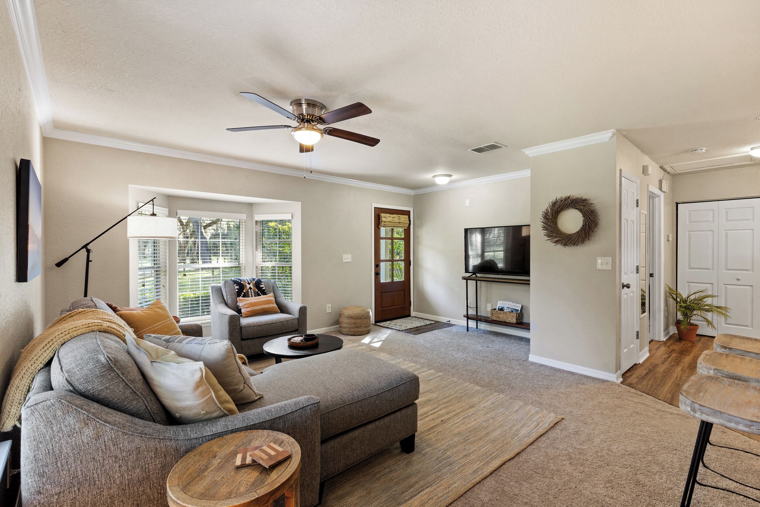 A living room with a sofa, ottoman, coffee table, and a ceiling fan.