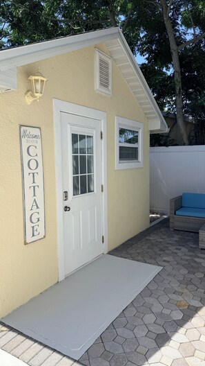 A cottage with a white door, a welcome sign, and a small window. - Fabulous 1-bedroom cottage with Patio in charming Sarasota (Sarasota)