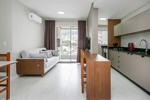 Eine moderne Wohnung mit Küchenzeile, einem Sofa, einem Esstisch und Blick auf die Stadt.