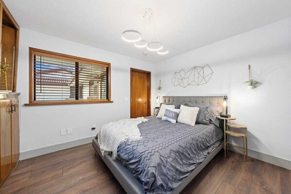 A bedroom with a bed, bedside table, and a window with blinds.