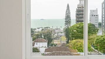 Quarto com uma grande janela com vista para a área costeira, incluindo edifícios e um corpo de água.