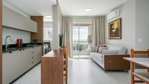 Una cucina moderna con un'isola centrale, una zona pranzo con tavolo e sedie, e un angolo living con divano e un quadro appeso al muro.
