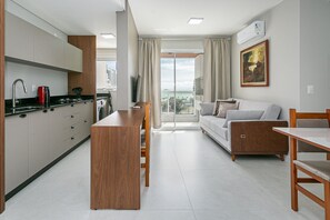 Una cocina moderna con una isla central, un comedor con mesa y sillas, y una sala de estar con un sofá y un cuadro en la pared.