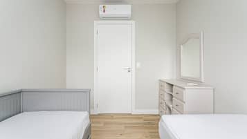 A bedroom with two beds, a dresser, a mirror, and an air conditioning unit.