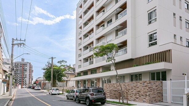 Un edificio residenziale a più piani con balconi, facciata in mattoni e auto parcheggiate sulla strada.