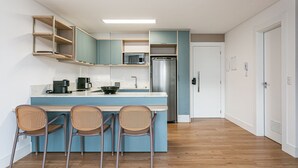 Uma cozinha moderna com ilha central, eletrodomésticos embutidos e área de refeições com cadeiras de vime.