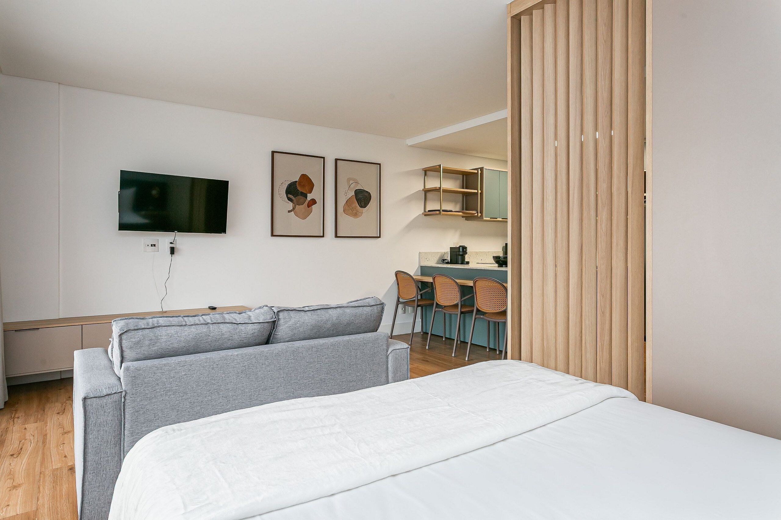 Una habitación de hotel moderna con cama, televisor y obras de arte en la pared.