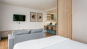 Quarto de hotel moderno com uma cama, televisão e obras de arte na parede.