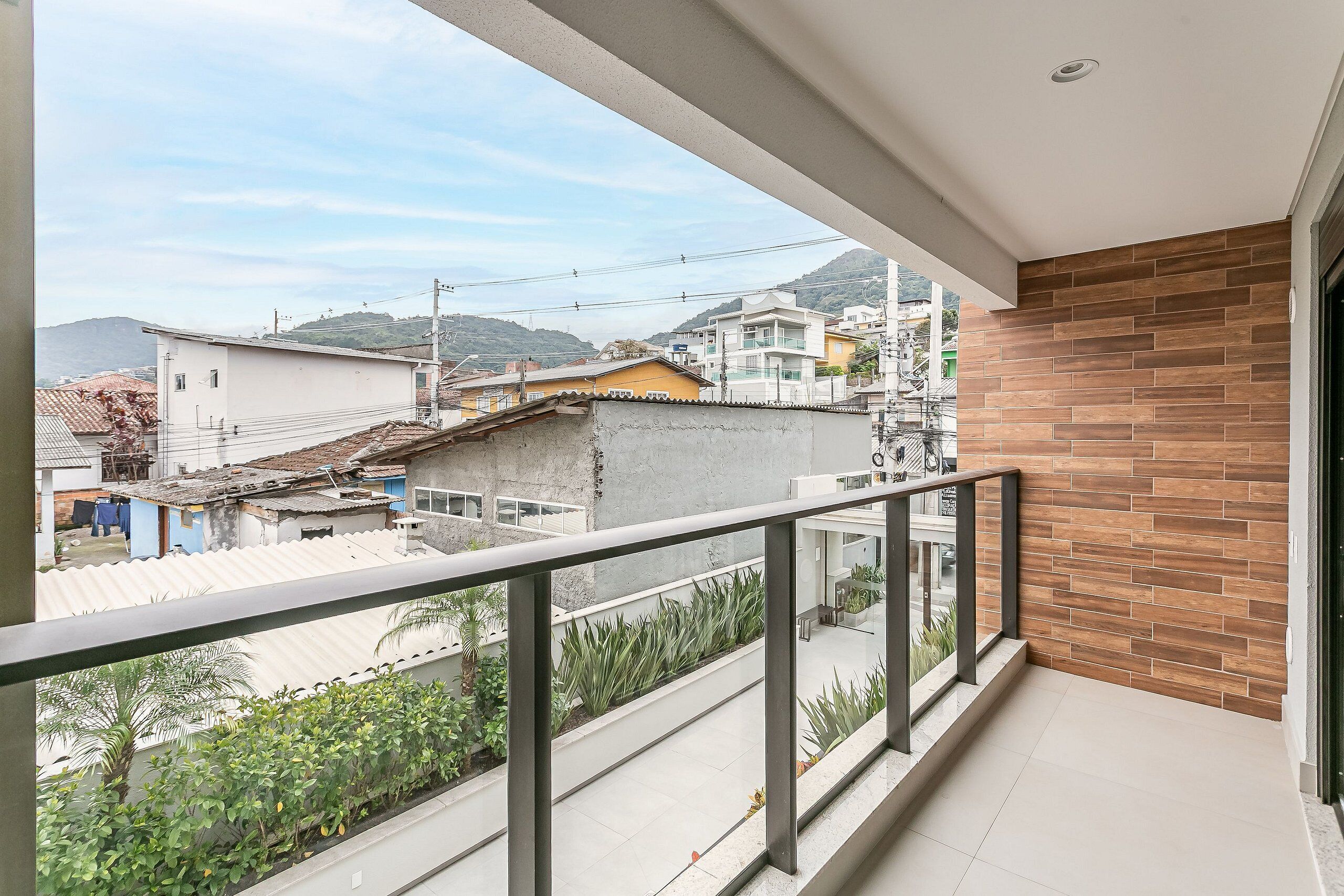 Un balcon donnant sur un quartier résidentiel, avec des maisons et un paysage vallonné.