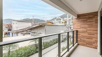 Un balcon donnant sur un quartier résidentiel, avec des maisons et un paysage vallonné.