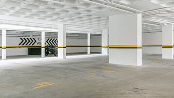 Eine überdachte Parkgarage mit weißen Säulen, deutlicher Beschilderung und einem Motorrad in einer Parkbox.
