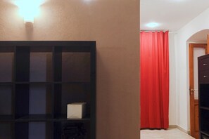 A room with a black shelving unit, a red curtain, and a wooden door. - Hostmate - Bari - Trento (Bari)