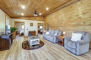 A spacious living room with a wooden ceiling, a gray sofa, a coffee table, and a television. - Designed for laid-back luxury in the mountains. Panoramic Views Escape to Nature (Butler)