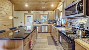 A modern kitchen with wooden cabinets, a stainless steel refrigerator, a microwave, and a stove.