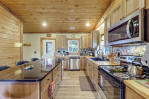 A modern kitchen with wooden cabinets, a stainless steel refrigerator, a microwave, and a stove.