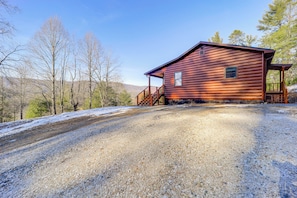 A rustic cabin with a gravel driveway, wooden deck, and a scenic mountain backdrop. - Designed for laid-back luxury in the mountains. Panoramic Views Escape to Nature (Butler)