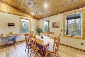A dining room with a wooden table, chairs, and a vase of flowers. - Designed for laid-back luxury in the mountains. Panoramic Views Escape to Nature (Butler)