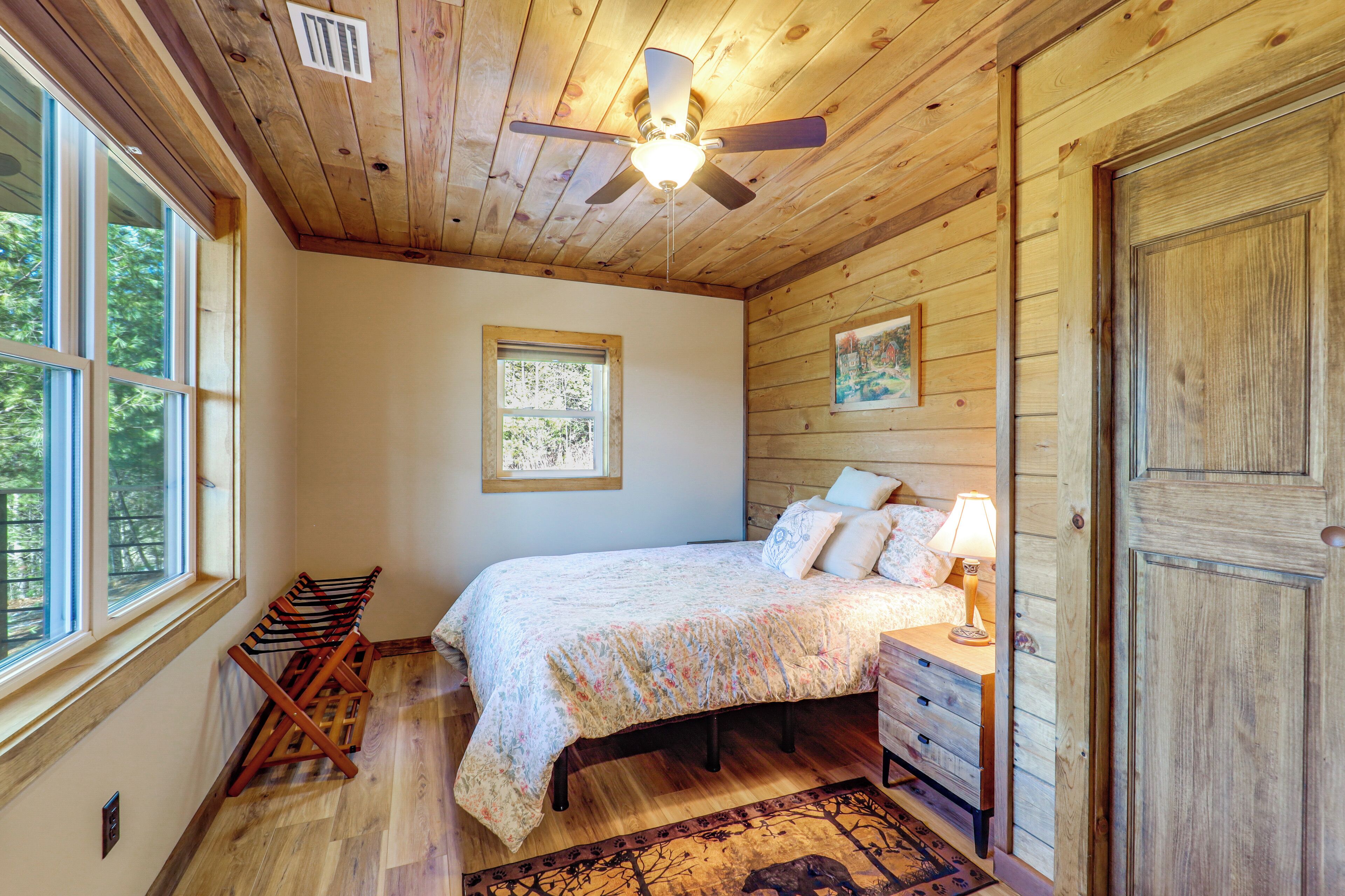 Une chambre à coucher avec un lit, une commode, une lampe et un ventilateur de plafond.