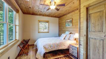 A bedroom with a bed, dresser, lamp, and a ceiling fan.