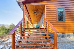 A wooden cabin with a staircase leading to a porch.