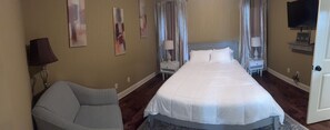 A hotel room with a bed, a chair, a nightstand with a lamp, and a television. - Oxford Condo Minutes from Ole Miss University (Oxford)