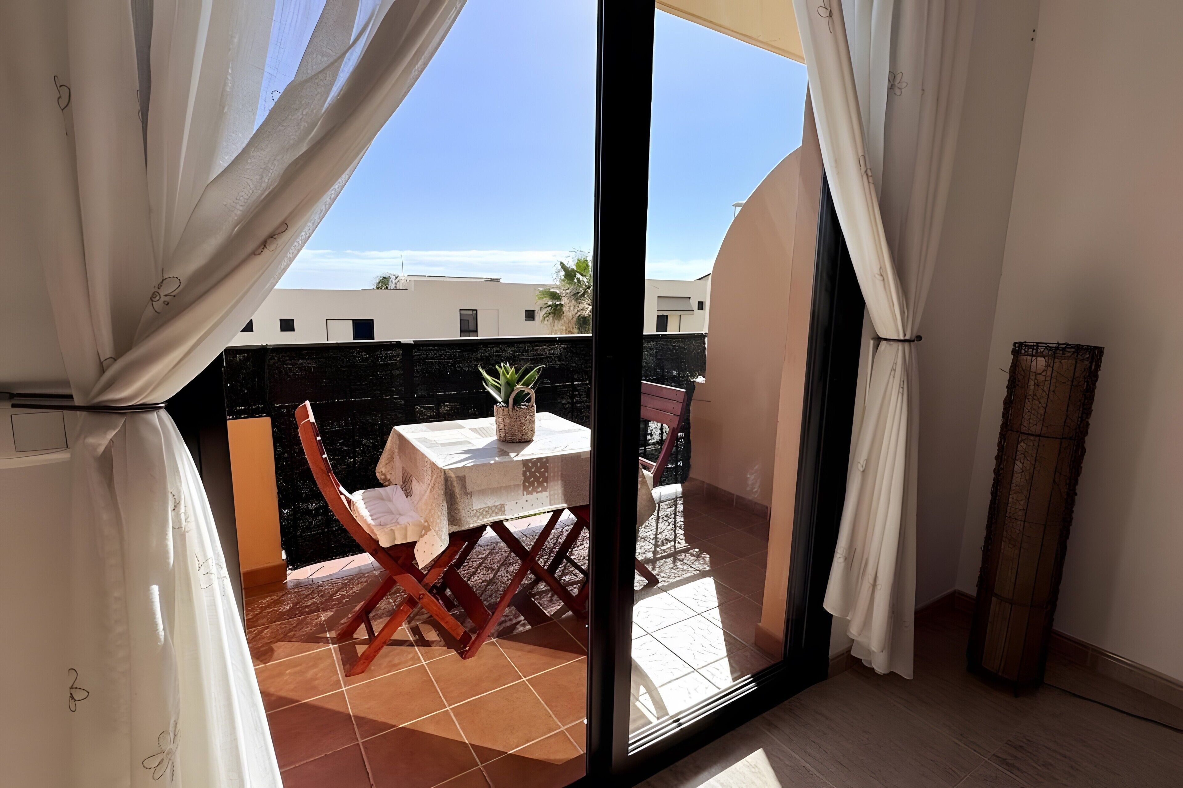 Un balcone con un tavolo, sedie e una pianta in vaso.