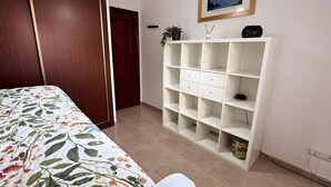 A bedroom with a bed, a white shelving unit, and a door leading to another room. - 'El Galeón' Bright Apartment with Partial Sea View, Pool, and Wi-Fi (Adeje)