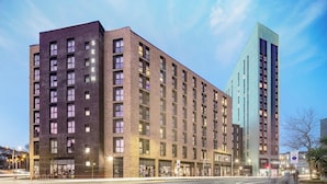 A multi-story hotel with a brick facade and a modern glass building adjacent to it. - Student Only Seren (Swansea)