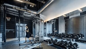 A gym with exercise equipment, a bench, and a rack of dumbbells. - Student Only Seren (Swansea)