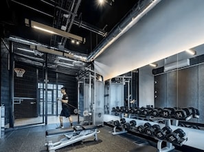 Ein Fitnessraum mit Trainingsgeräten, einer Bank und einem Dumbbell-Gestell.