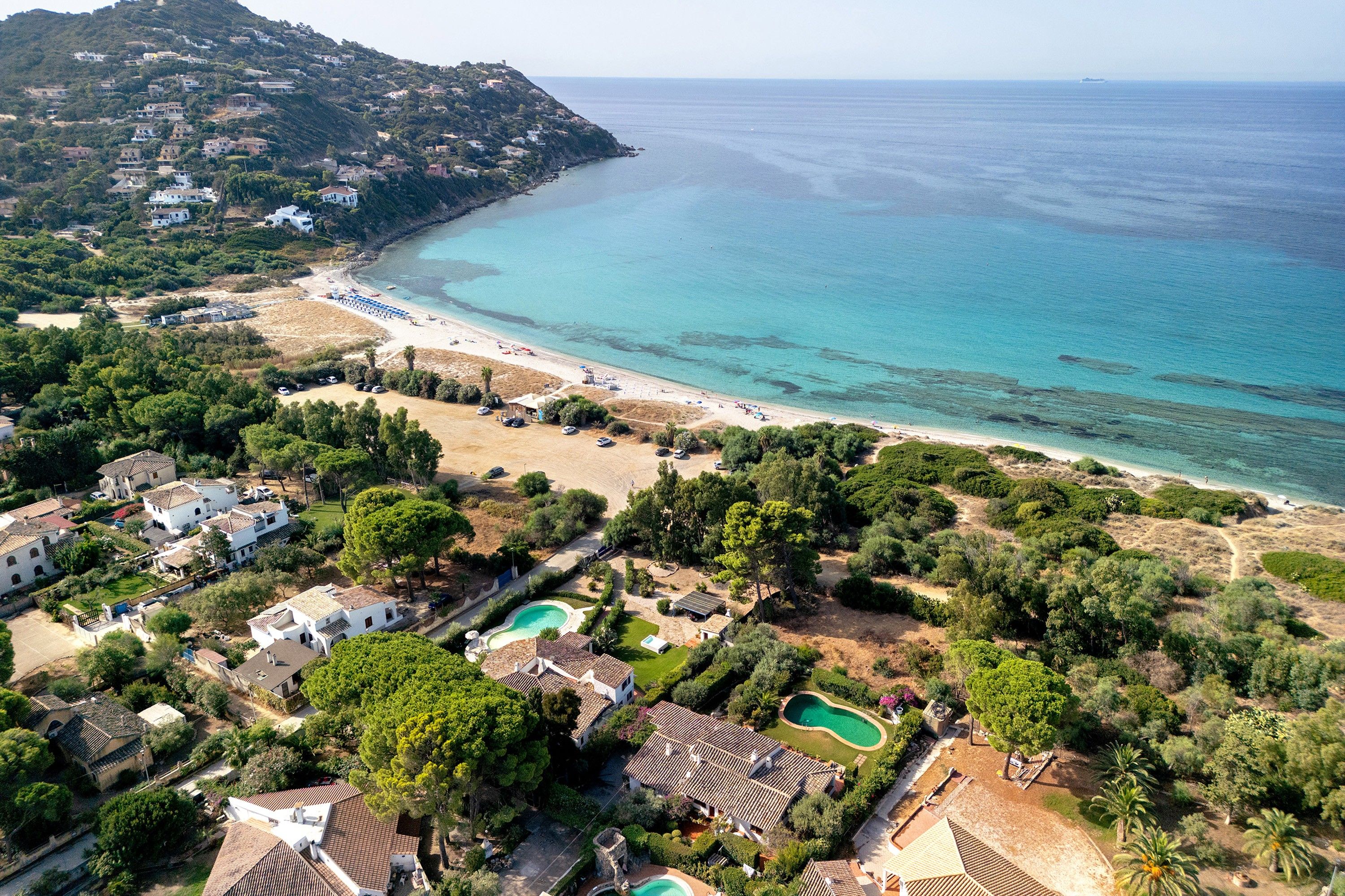 A coastal property with multiple buildings, a beach, and a clear view of the sea.