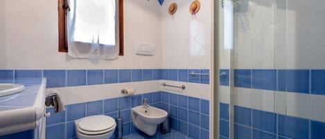 A bathroom with a toilet, bidet, and a glass-enclosed shower area.