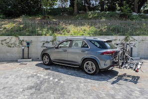 Um SUV prateado estacionado numa área pavimentada com suporte para bicicletas na parte traseira.