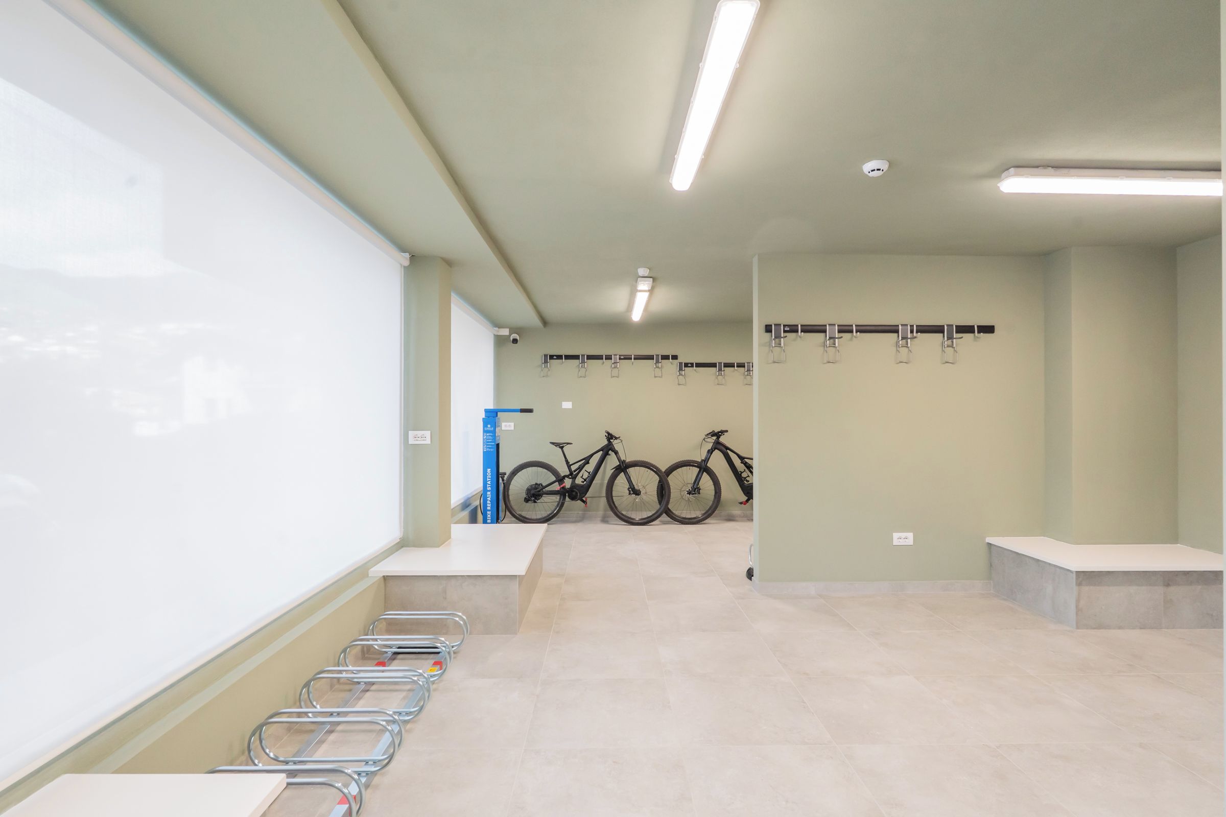 Ein sauberer, gut beleuchteter Innenraum mit einer Tafel, einer Fahrradwerkstatt und einem an der Wand befestigten Fahrradständer.