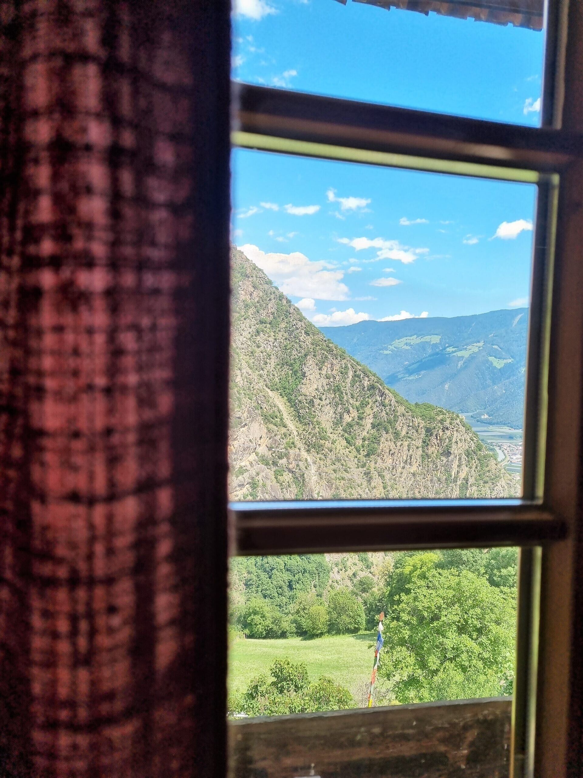 Een raam met uitzicht op een bergachtig landschap.