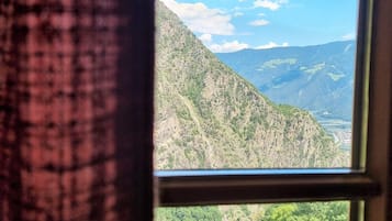 Een raam met uitzicht op een bergachtig landschap.