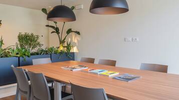 Uma sala de jantar moderna com uma mesa de madeira, cadeiras cinzas e duas luminárias pendentes.