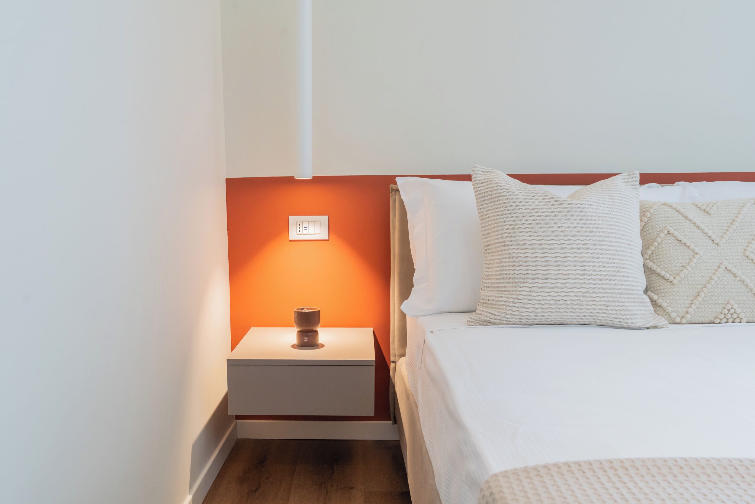 Ein Hotelzimmer mit einem Bett, einem Nachttisch, einer Lampe und einer Steckdose.