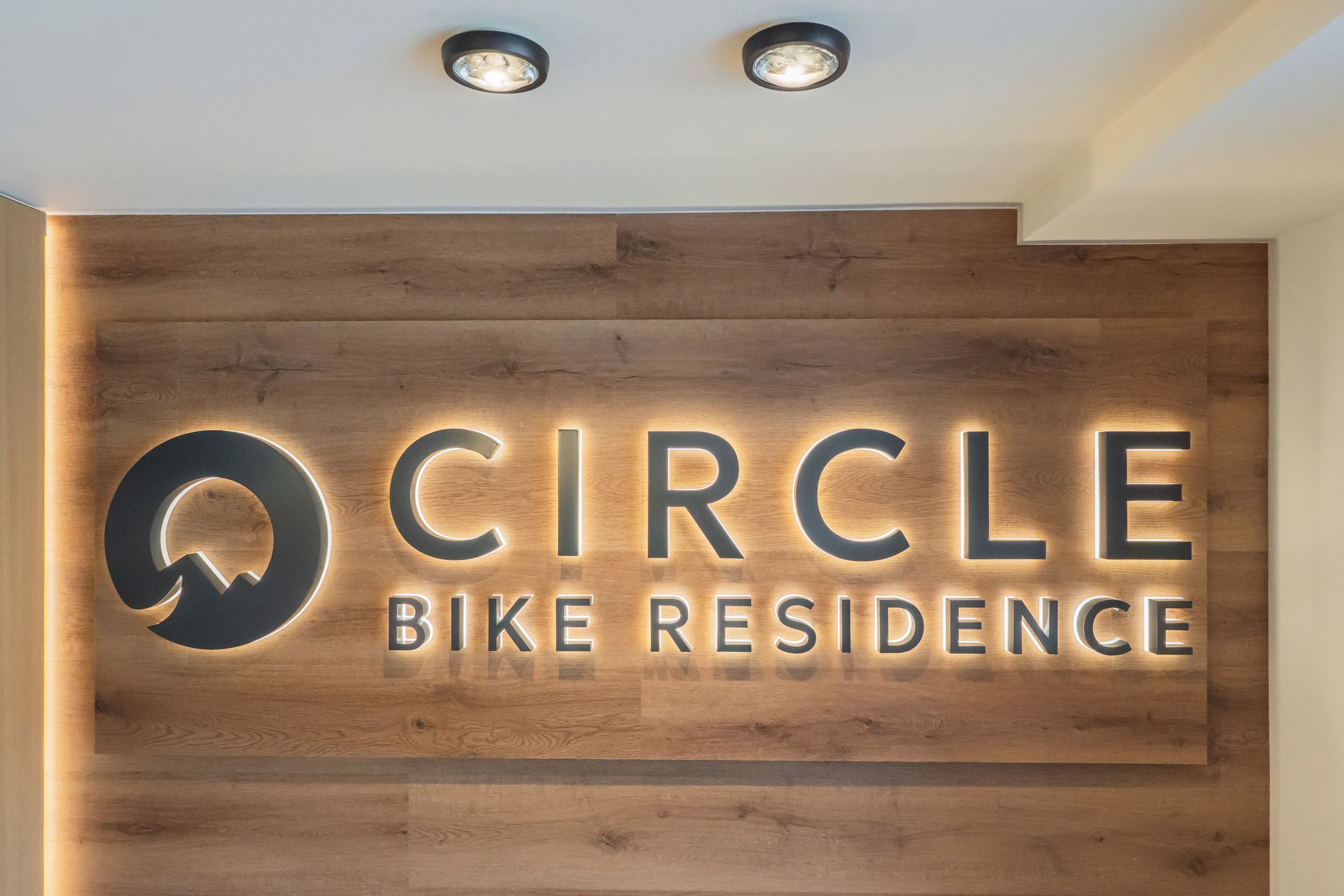 Eine Holzwand mit beleuchteter Beschilderung für 'Circle Bike Residence'.