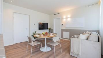 Uma sala de estar moderna com área de jantar, um sofá e uma televisão de tela plana na parede.