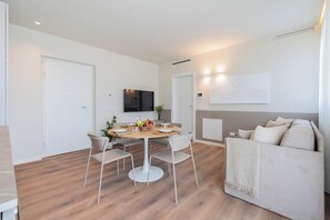 Un salon moderne comprenant un coin repas, un canapé et un téléviseur à écran plat fixé au mur.