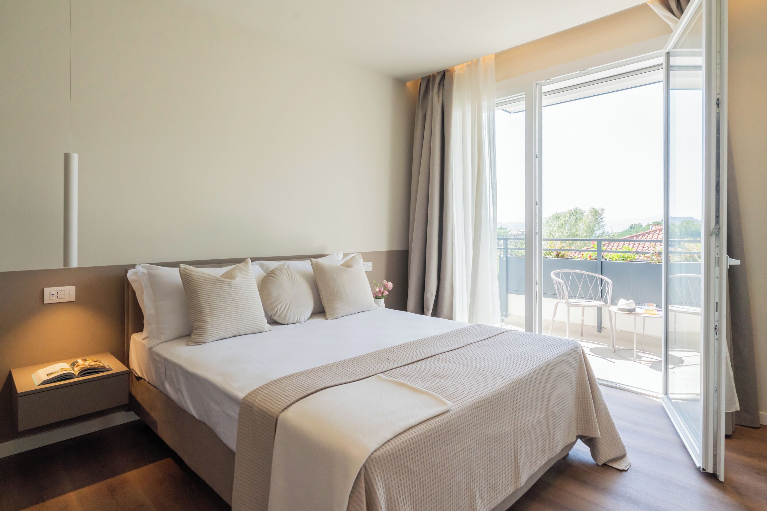 Ein Hotelzimmer mit Bett, Nachttisch und Blick ins Freie.