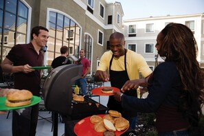 A barbecue setup with people cooking and serving food.