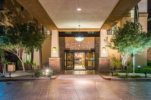 A hotel entrance with a stone facade, glass doors, and a hanging light fixture.