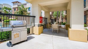 A covered outdoor patio with a barbecue grill, seating area, and poolside view. - Accessible 1BR 2 Queen Suite | Pool + Breakfast! (Glendale)