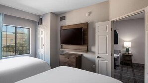 A hotel room with two beds, a TV mounted on the wall, a desk with a lamp, and a view of the outside. - Accessible 1BR 2 Queen Suite | Pool + Breakfast! (Glendale)