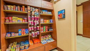 A candy and snack display in a store with various products on shelves and a sign above.