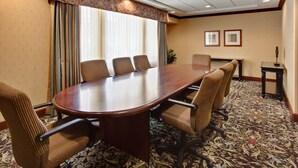 A conference room with a large wooden table, six chairs, and a patterned carpet.