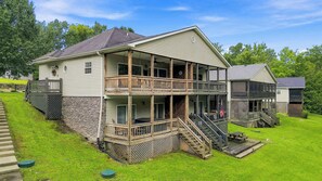 Ein zweistöckiges Haus mit Balkon, überdachter Veranda und Natursteinfundament.